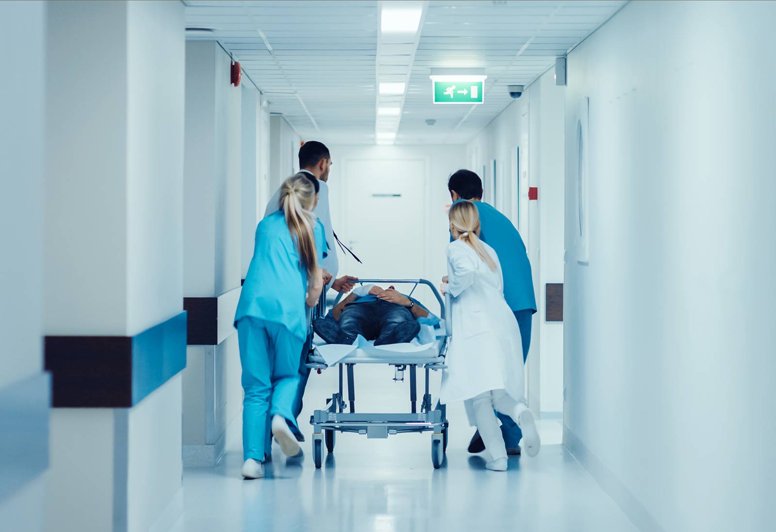 Doctors, Nurses and Paramedics Push Gurney with Seriously Injured Patient towards the Operating Room